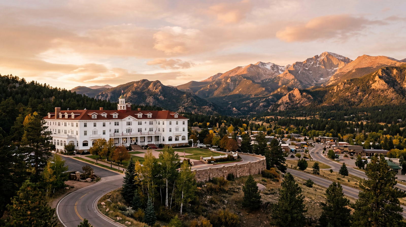 Iconic white Georgian revival hotel overlooking Rocky Mountain National Park in Colorado, warm editorial travel photography, golden hour, photorealistic, no text, no watermark, 16:9