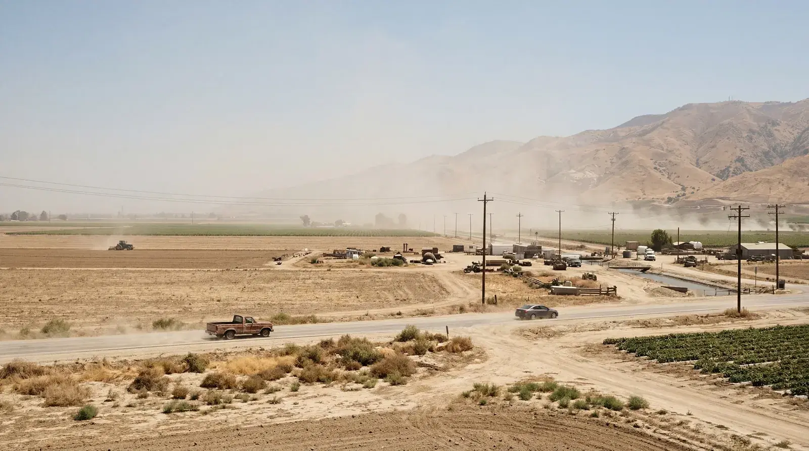 Flat hazy agricultural outskirts of Bakersfield California, smoggy valley air, intense sun bleaching the landscape, dry brown hills in background. documentary travel photography, realistic, no text, no watermark, 16:9