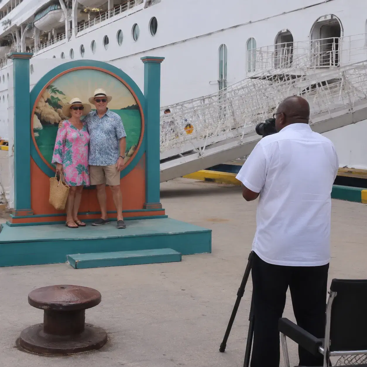 Realistic editorial photo of cruise passengers gathered around an excursion sign near a port bus, backpacks and sun hats