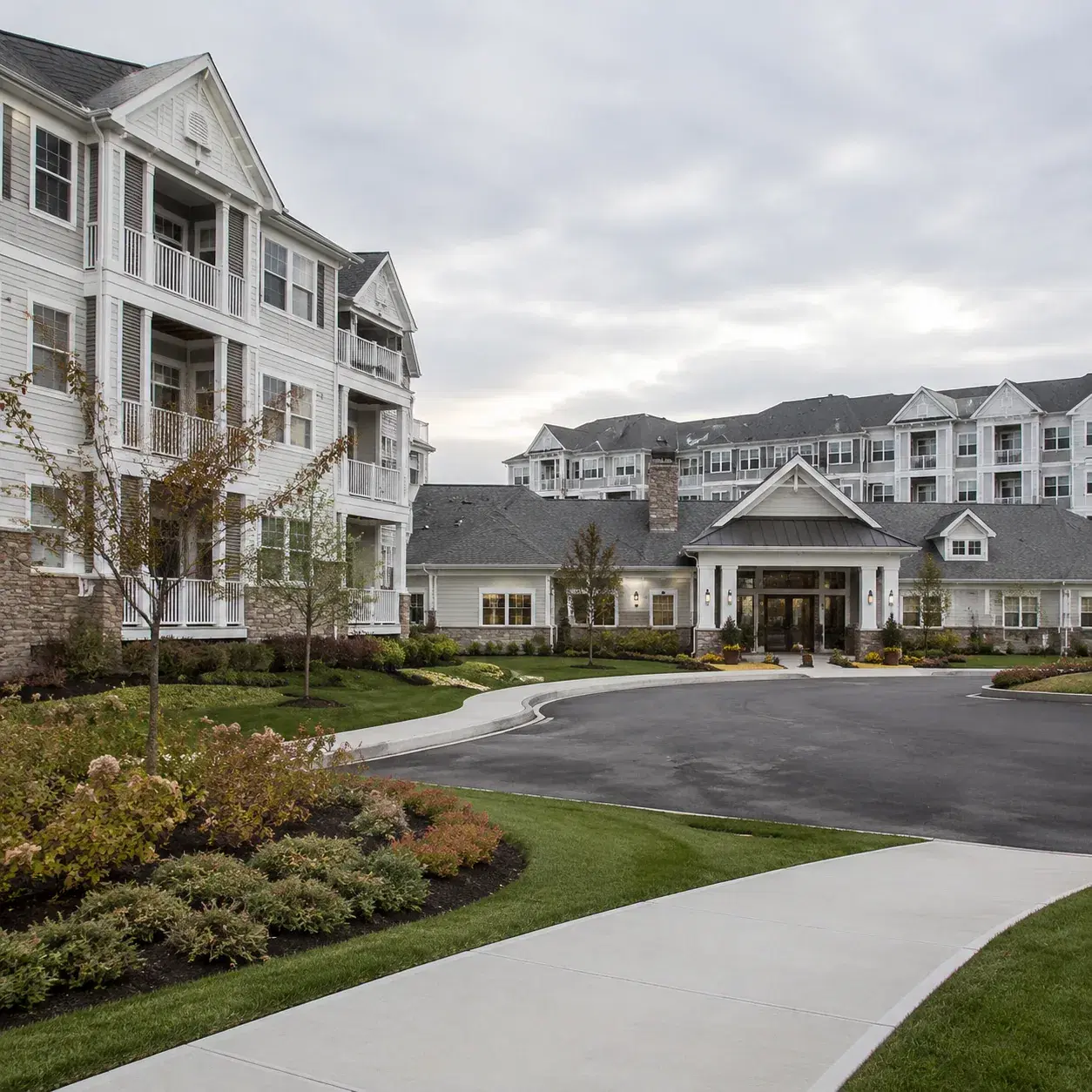 Realistic editorial photo of an upscale Long Island active adult condo community with mid-rise buildings, balconies, a c
