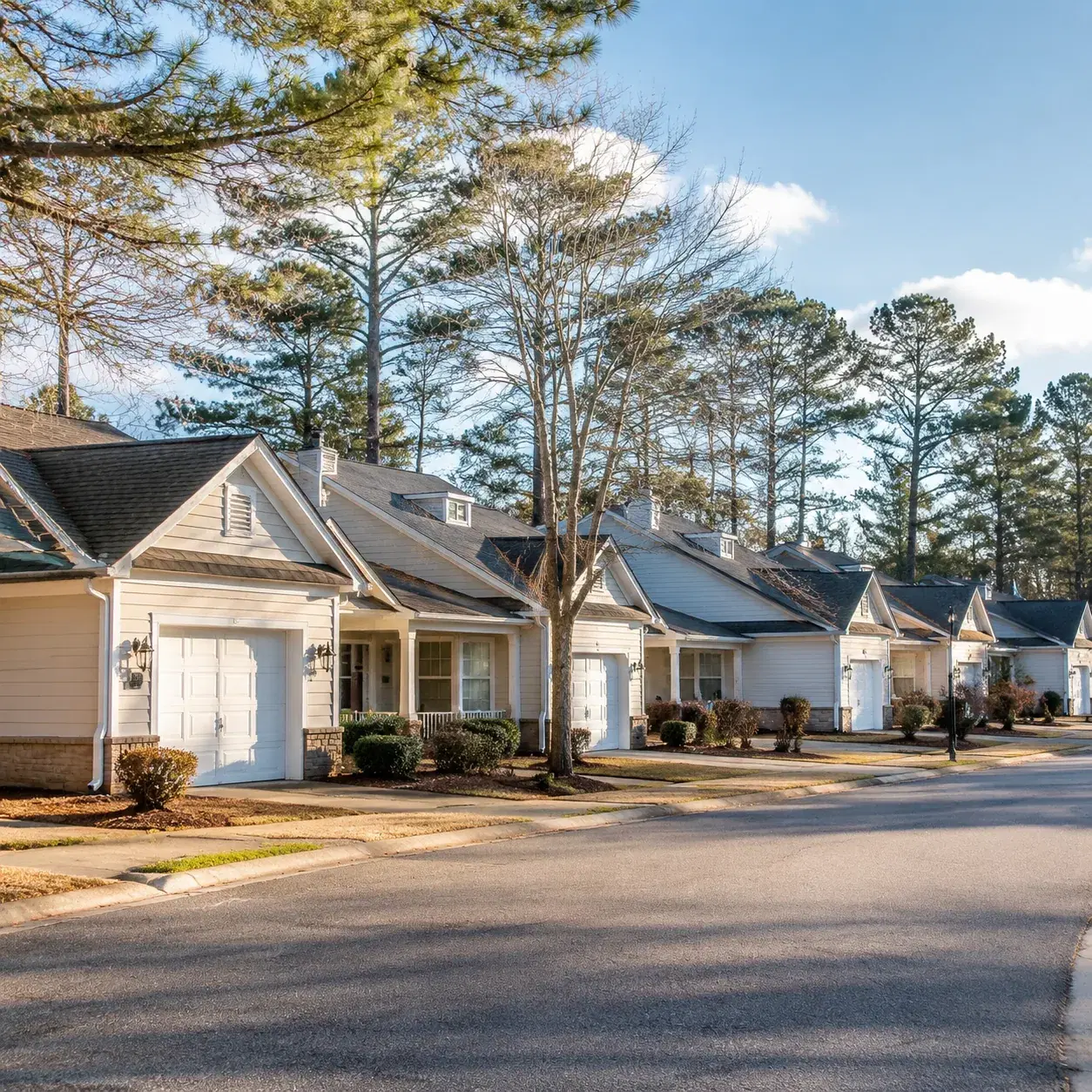 Realistic editorial photo of a Manchester New Jersey active adult community with attached homes, pine trees, quiet roads