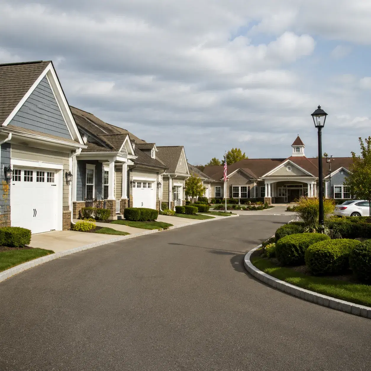 Realistic editorial photo of a quiet New Jersey coastal retirement community street with attached homes, a clubhouse ent