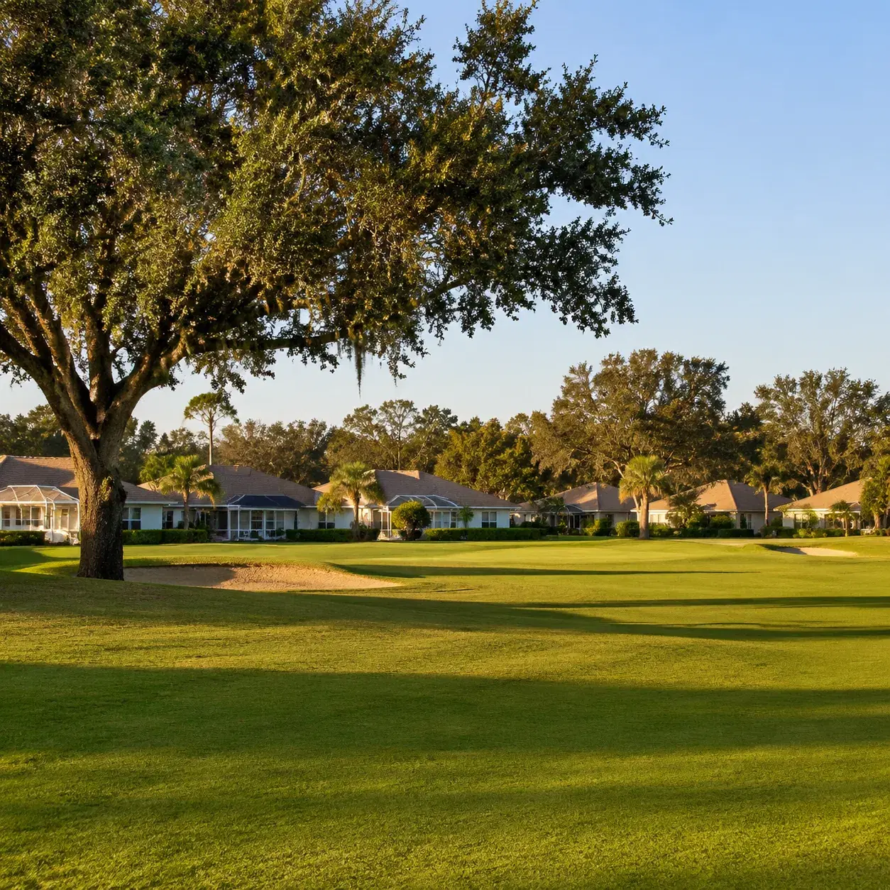 Realistic editorial photo of a quiet Citrus County Florida retirement community with rolling golf fairway, low homes, oa