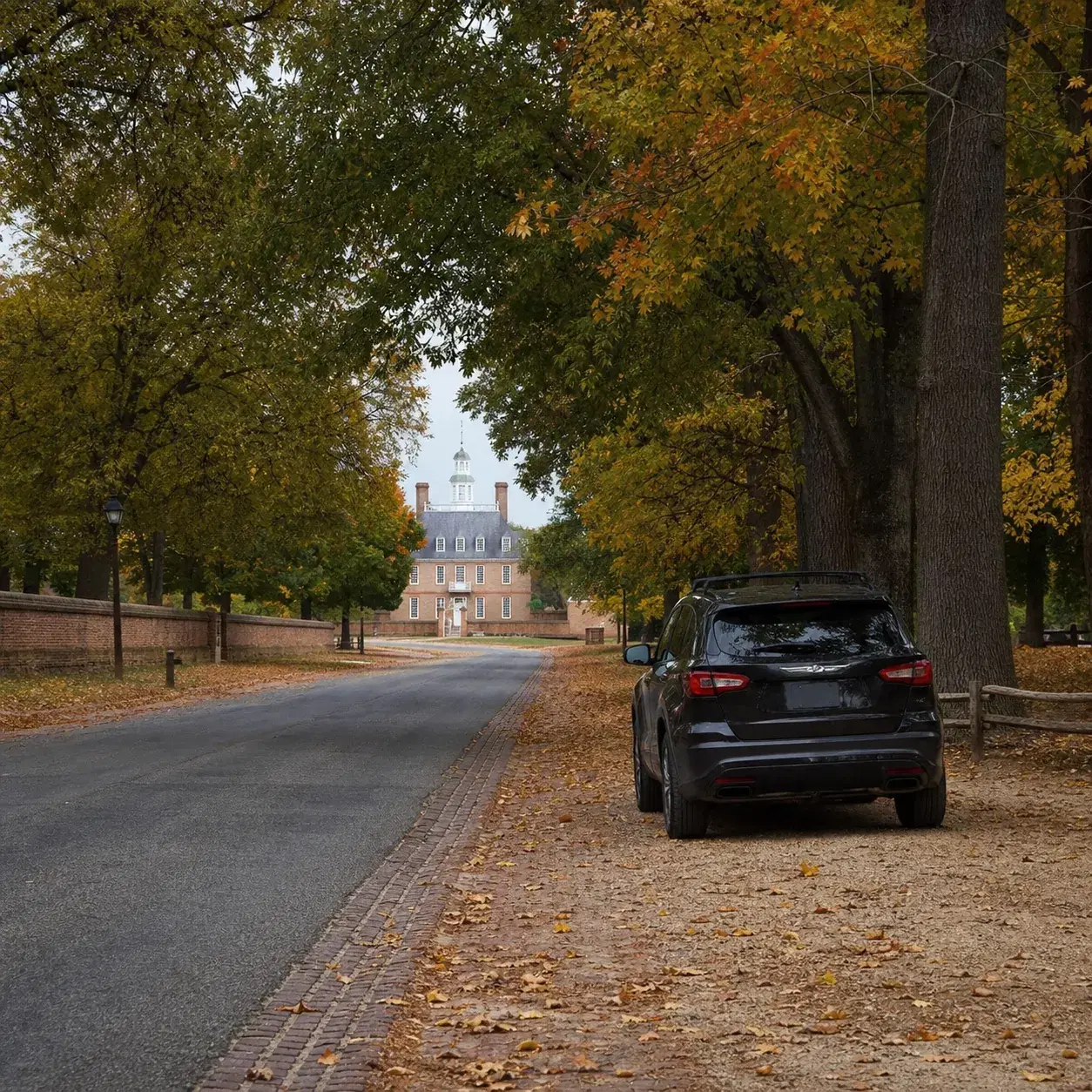 Realistic editorial photo of a tree-lined historic parkway in Virginia with brick-edged road texture, fall leaves, and a