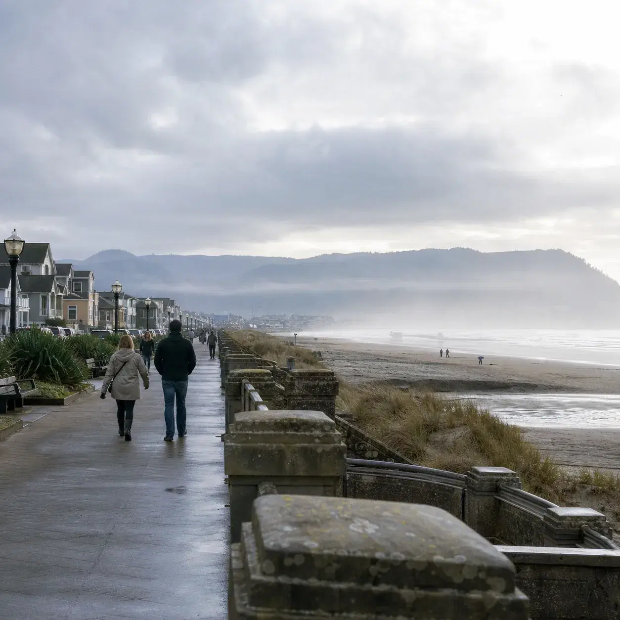 Realistic editorial photo of the Seaside Oregon promenade with a misty Pacific beach, low coastal buildings, walkers in 