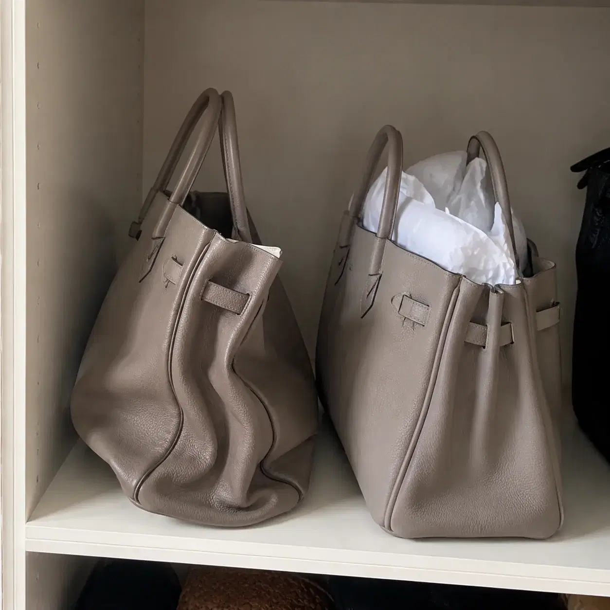 Realistic editorial photo of a structured handbag with collapsed corners and dented sides sitting next to a bag stuffed