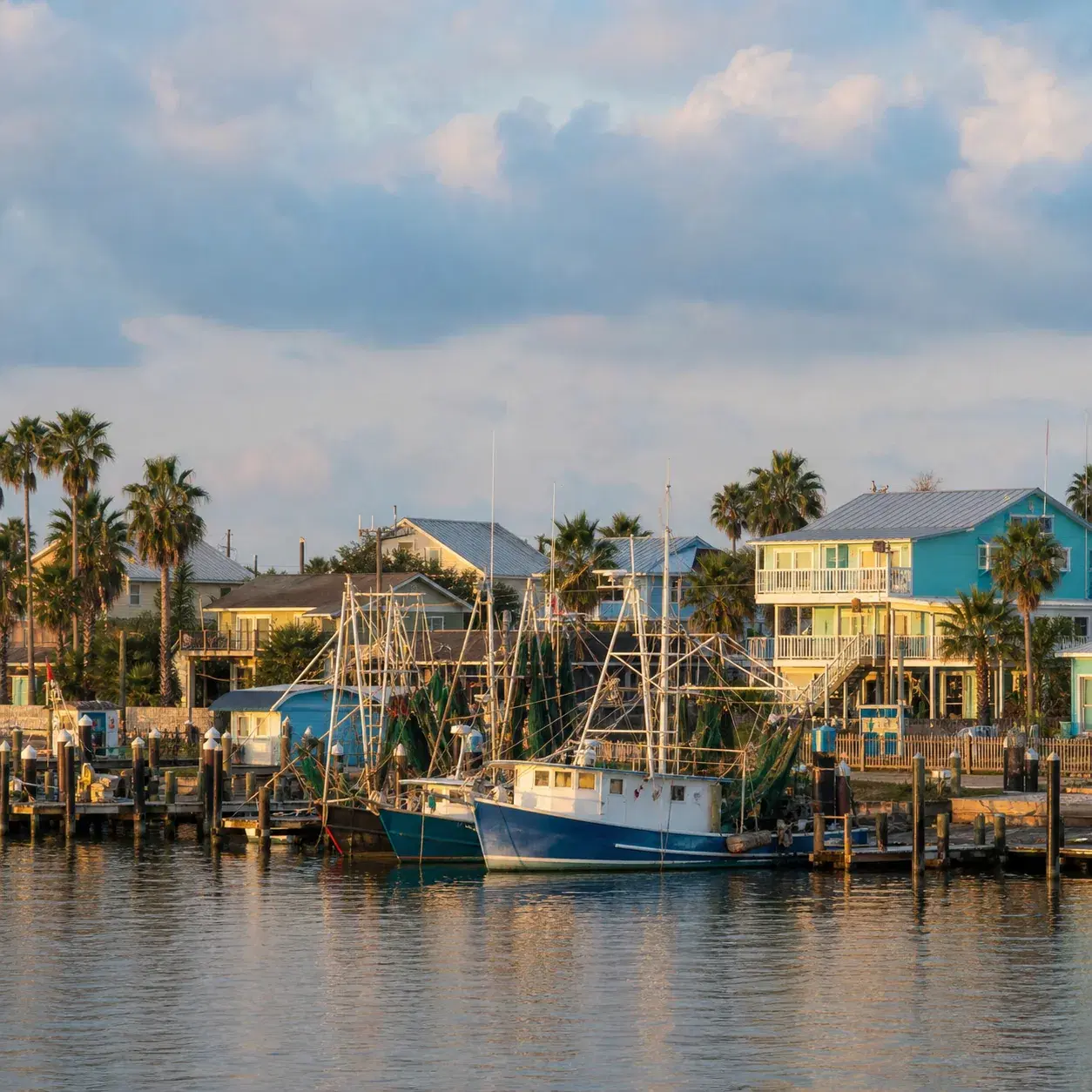 Realistic editorial photo of Rockport Texas harbor with shrimp boats, coastal cottages, palms, and warm Gulf Coast light