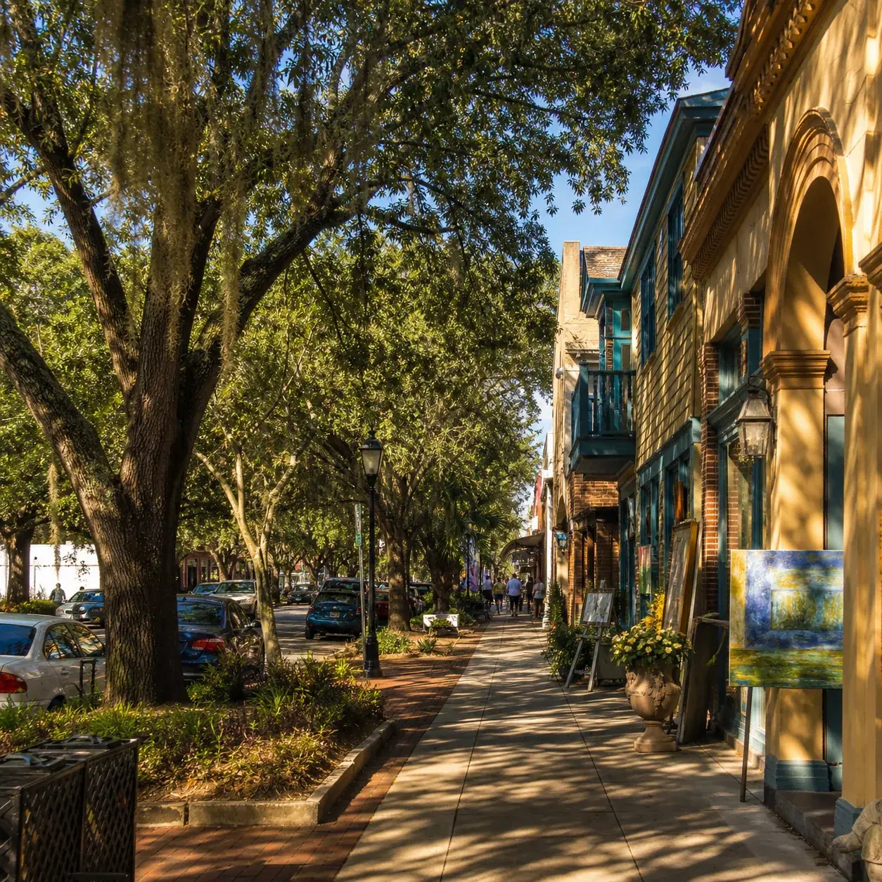 Realistic editorial photo of Ocean Springs Mississippi downtown with oak trees, art galleries, colorful storefronts, and