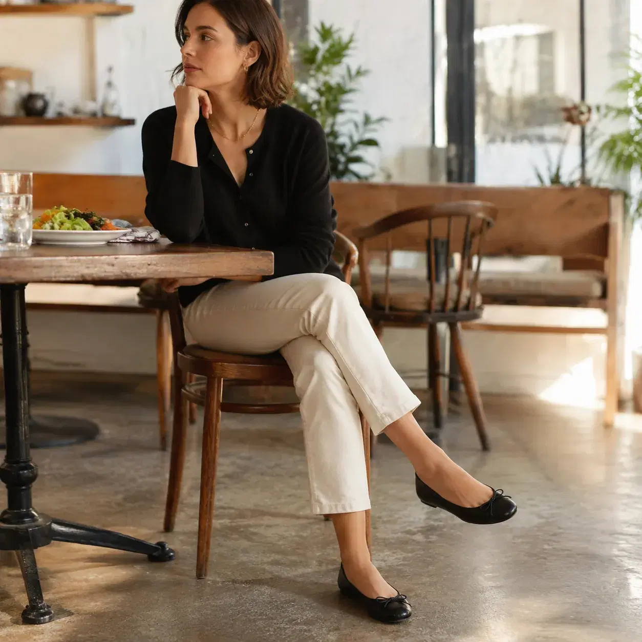 Realistic editorial photo of thin ballet flats with flat soles worn with ankle pants in a bright brunch cafe, shoes and