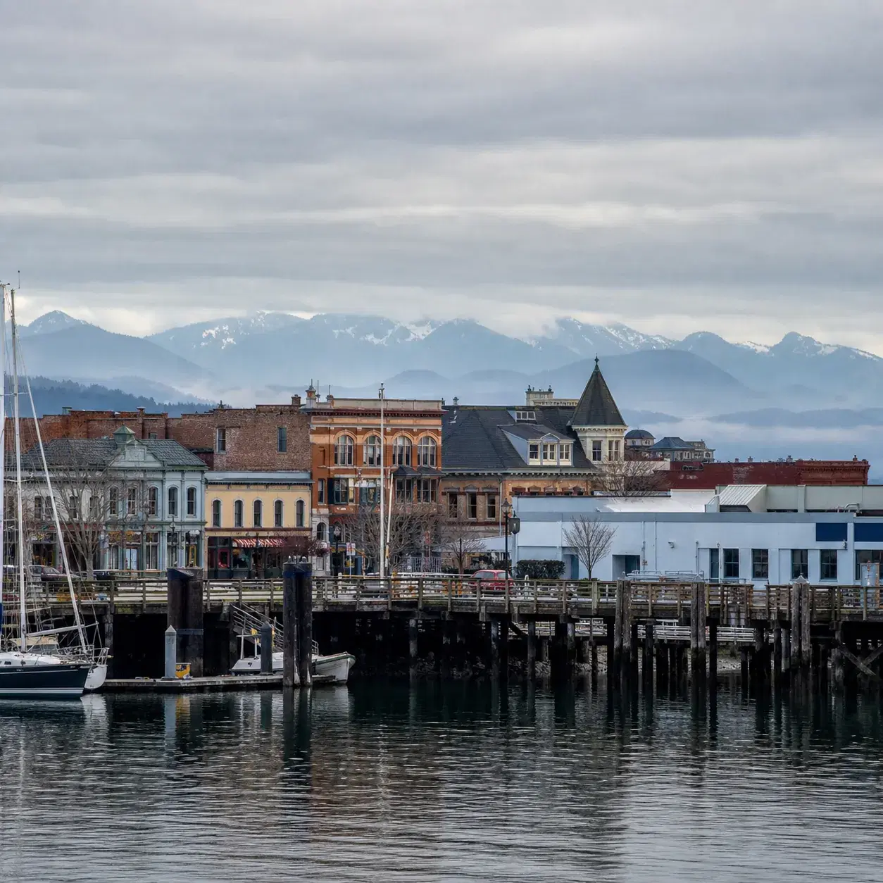 Realistic editorial photo of Port Townsend Washington Victorian seaport with historic brick buildings, marina masts, mou