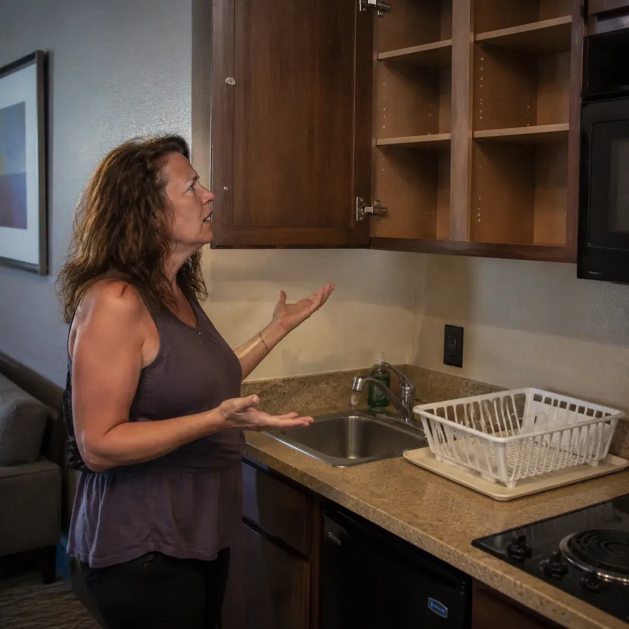 Residence Inn hotel kitchenette area with worn countertop, missing utensils, empty dish rack, middle-aged American woman