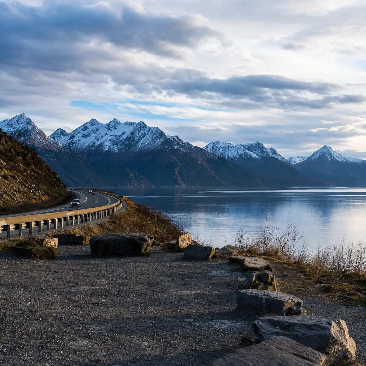 Realistic editorial photo of Alaska's Seward Highway beside Turnagain Arm with mountains, water, and a scenic pull-off u