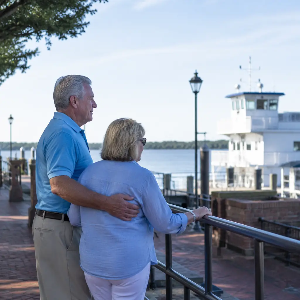 mature couple near the peaceful riverfront and ferry dock in St Marys Georgia on a clear weekday, realistic travel edito