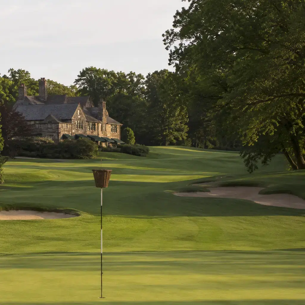 Realistic editorial photo of a historic Pennsylvania private golf course with wicker basket style flag without readable 