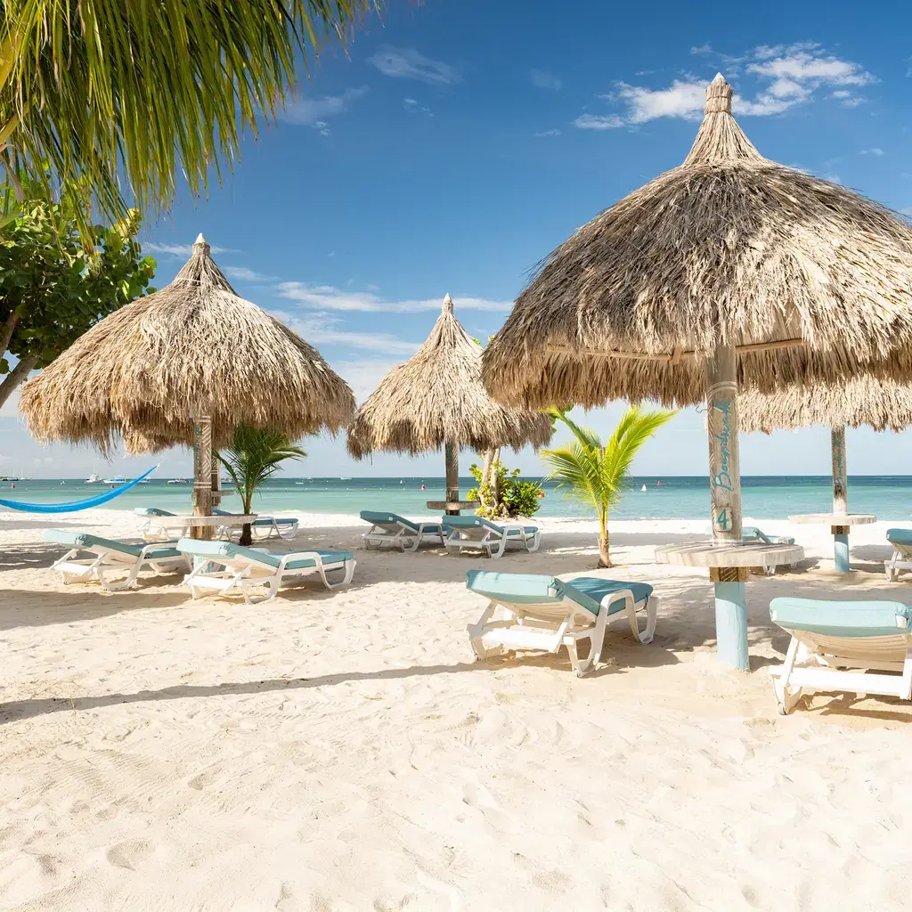 Palapa umbrellas and loungers at the Boardwalk Boutique Hotel beach area in Aruba