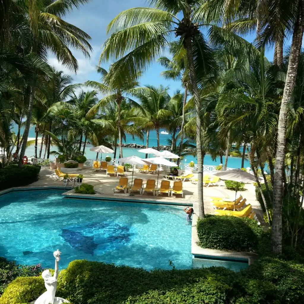 Palm-shaded pool and tropical gardens at Coco Reef Resort in Tobago