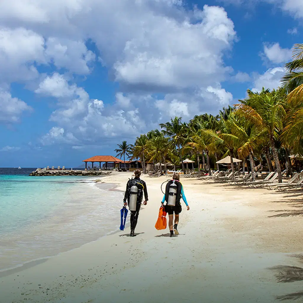 Scuba divers walking into the water from Harbour Village Bonaire