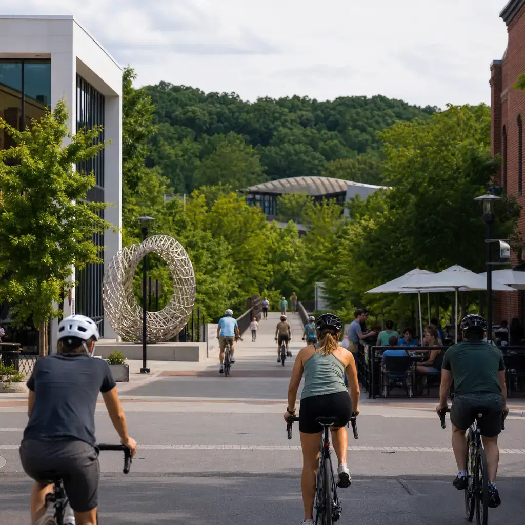Realistic editorial travel photo of cyclists leaving Bentonville's downtown square for the Razorback Greenway with publi