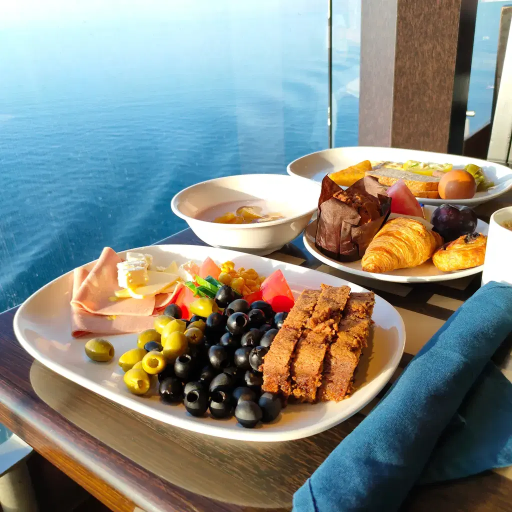 Buffet breakfast plates on a cruise ship table overlooking the sea
