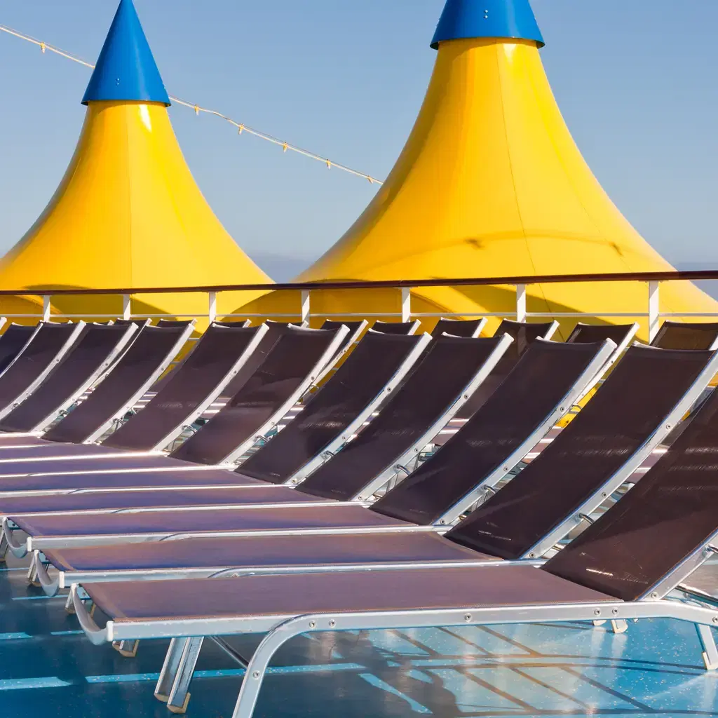 Rows of sun loungers beside a cruise ship pool