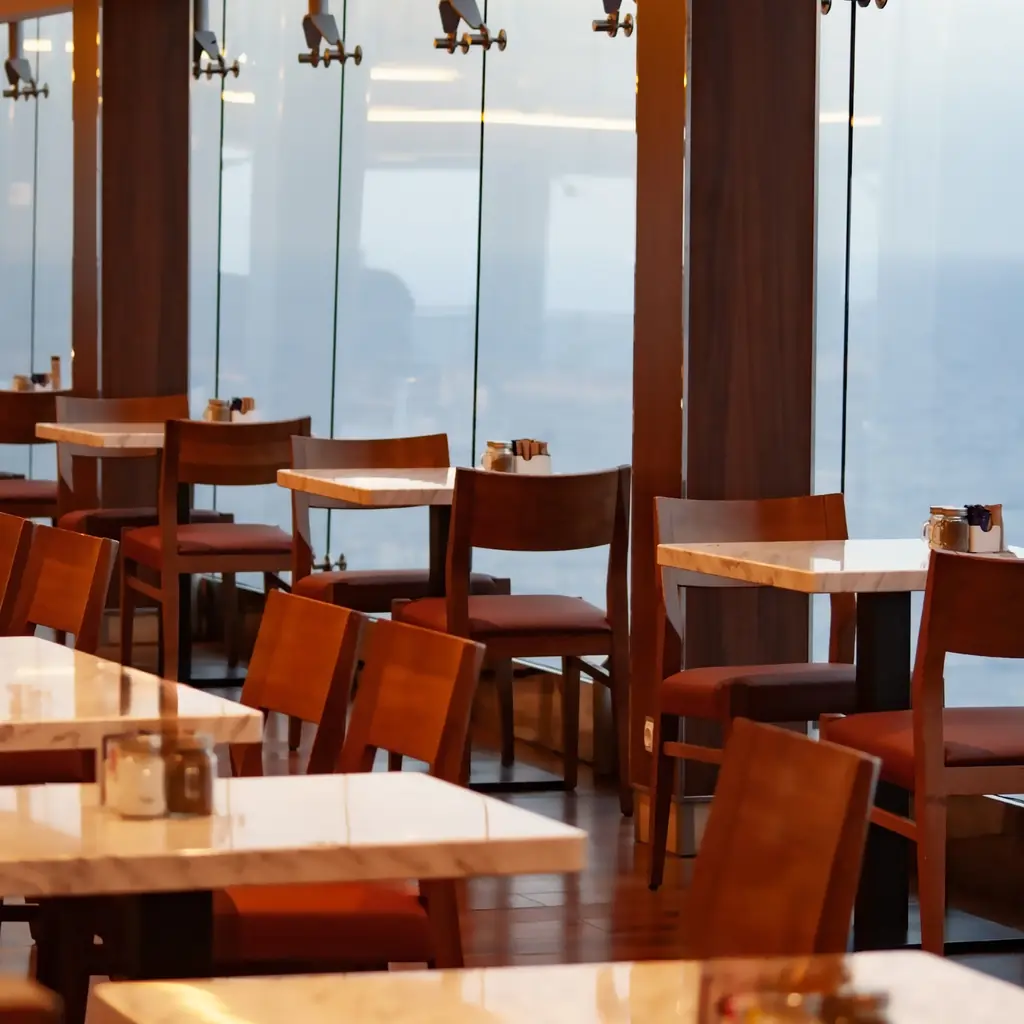 Tables and chairs in a cruise ship dining area with sea views