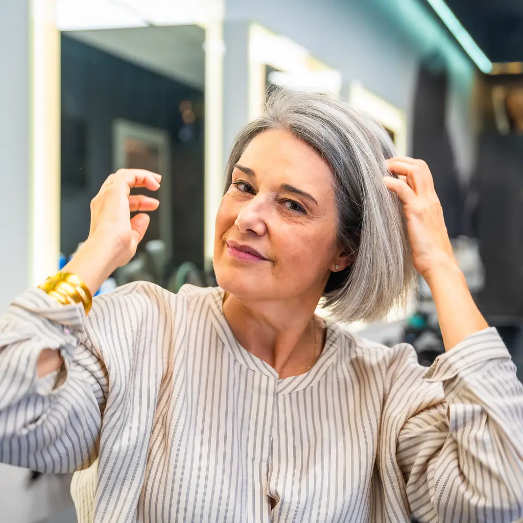 A woman adjusting her softly shaped silver bob