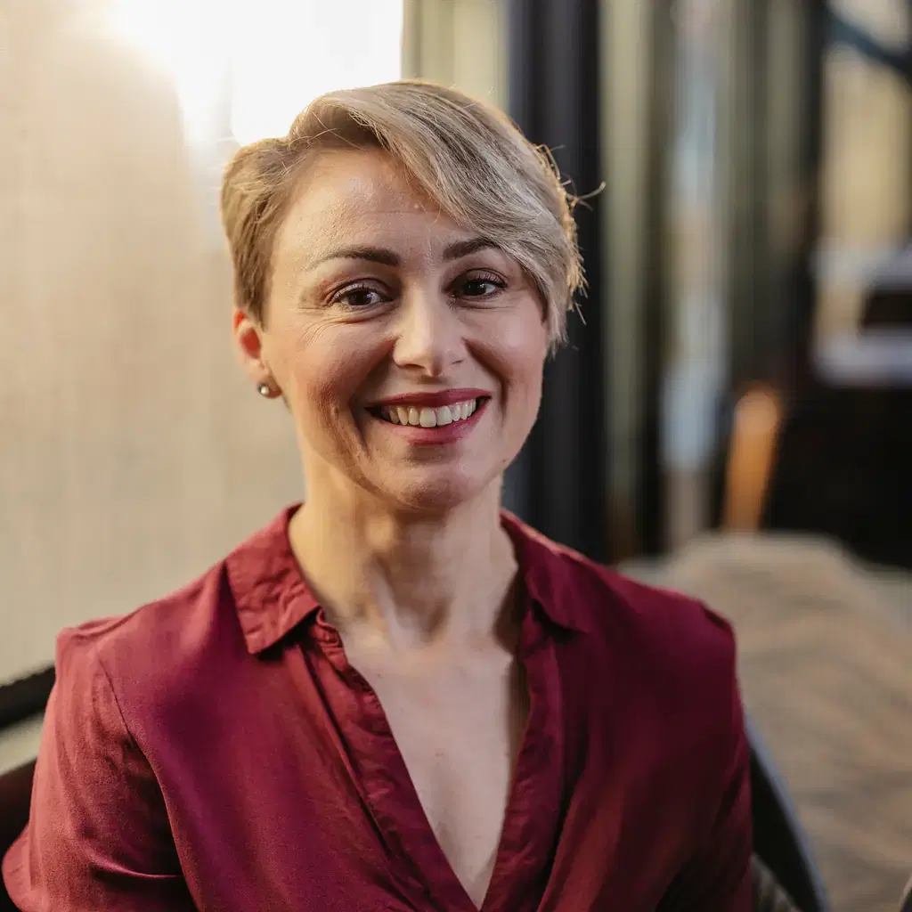 A smiling woman with a longer pixie cut swept to one side