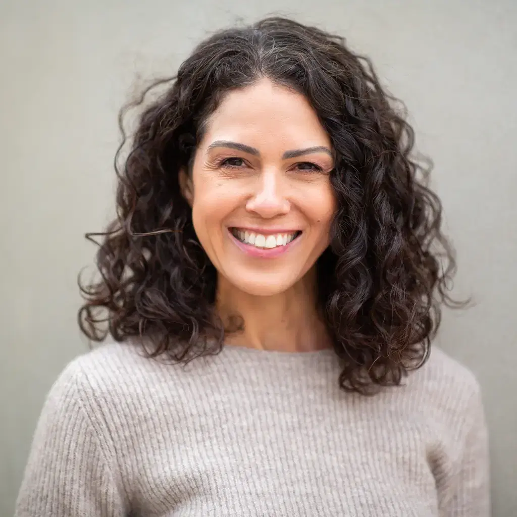 A smiling woman wearing her naturally curly shoulder-length hair loose