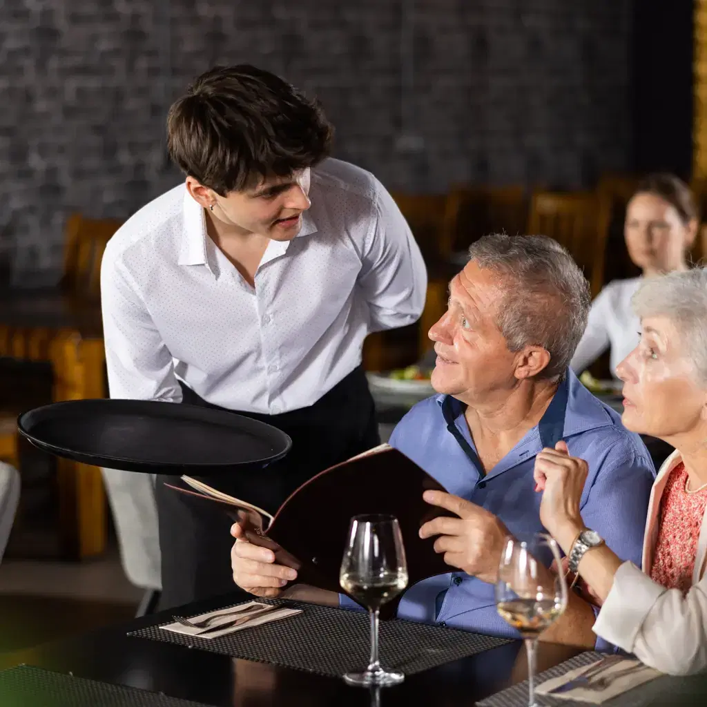A waiter answering a couple’s menu questions