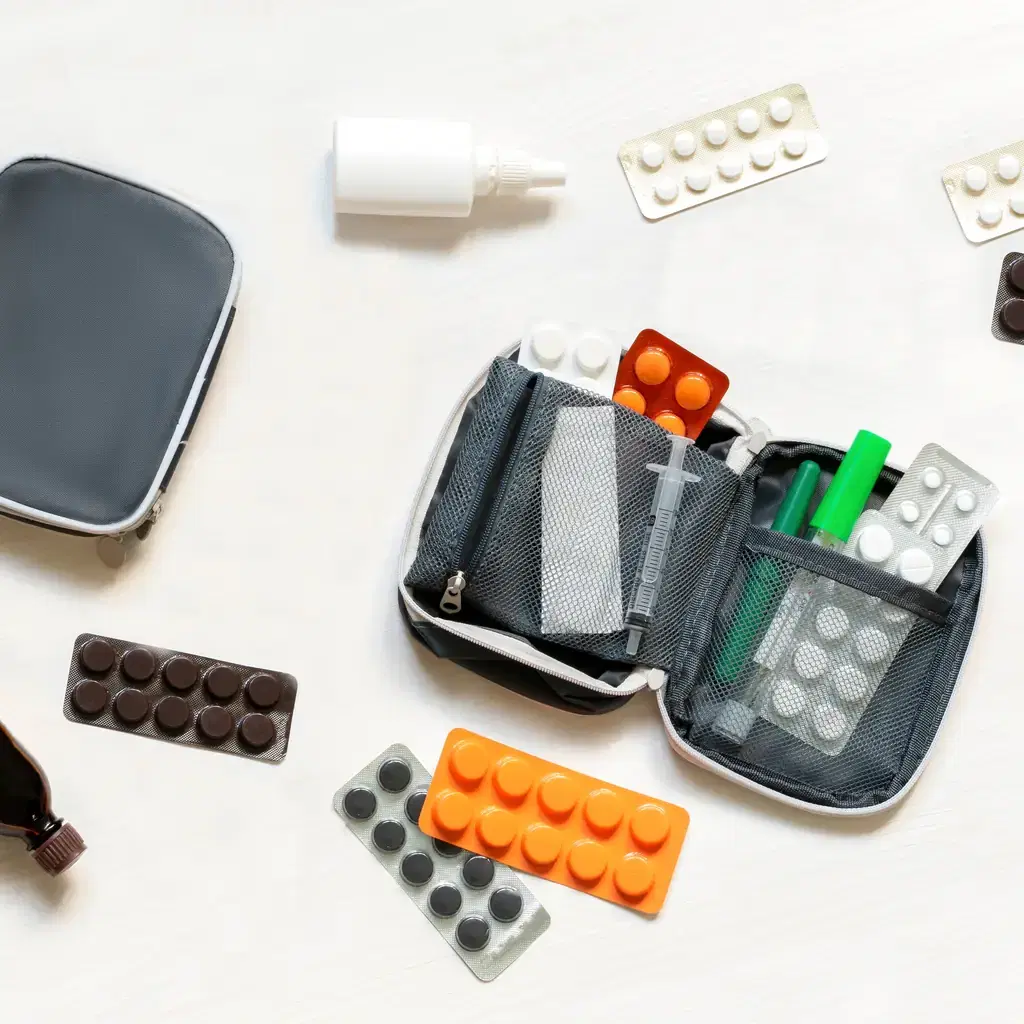 Medication and personal supplies arranged beside a travel pouch