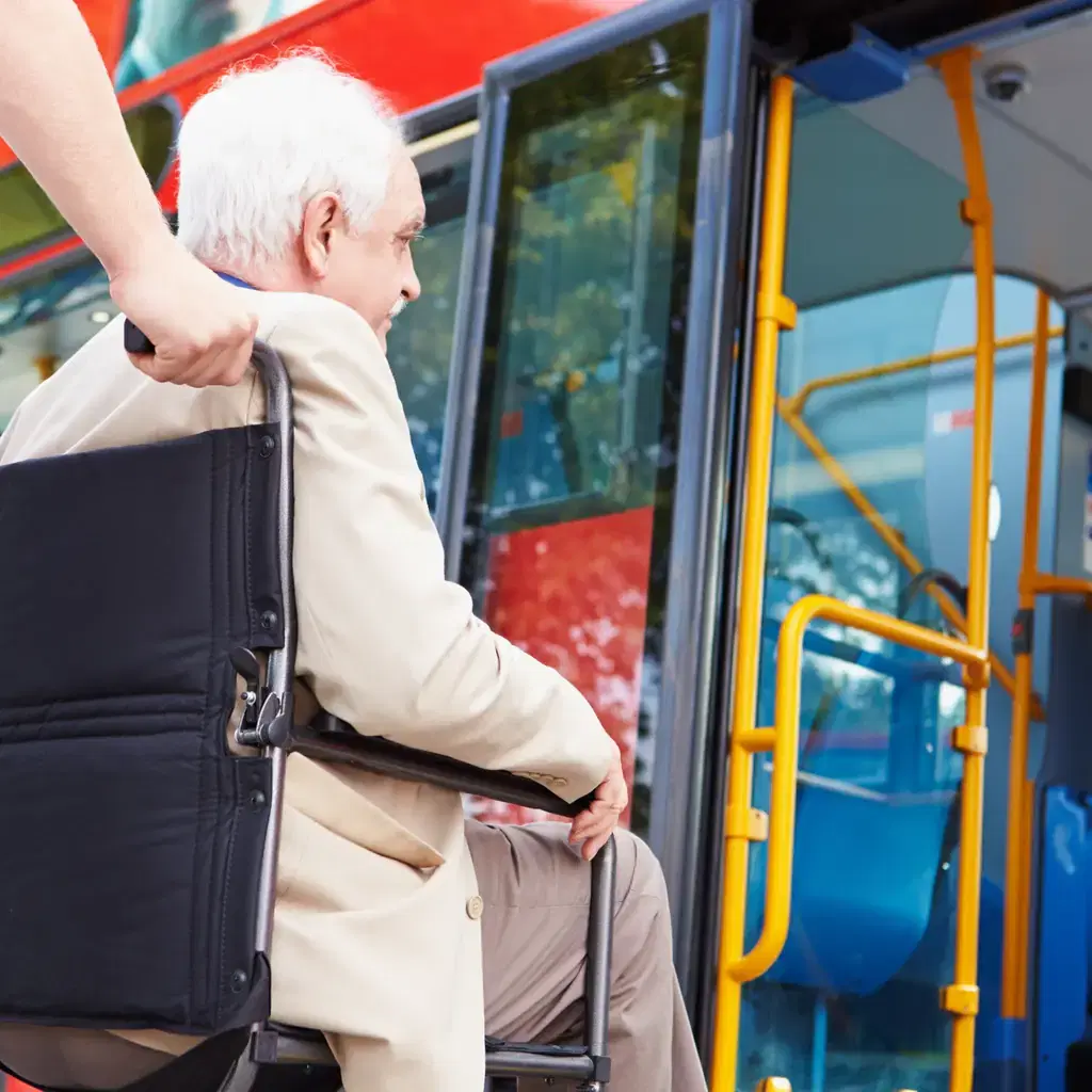 An older passenger using the handrail while boarding a bus