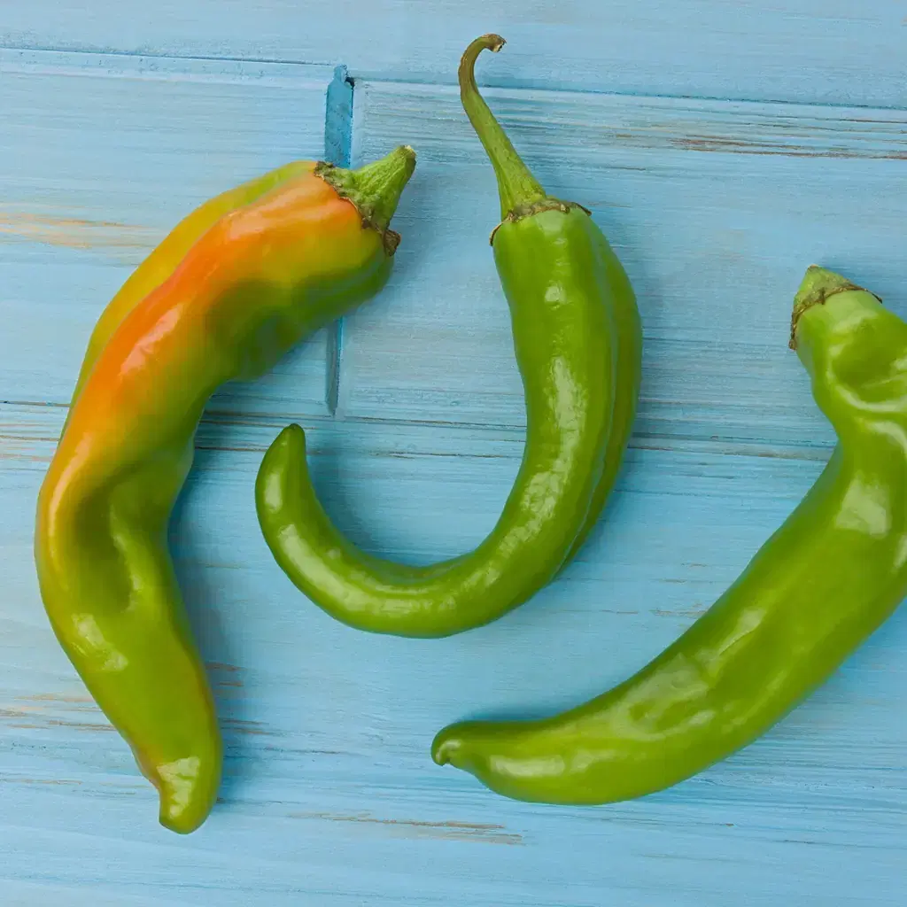 Green chile peppers on a blue wooden surface.