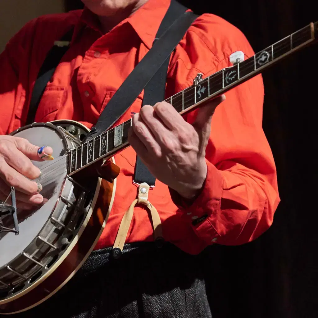 Illustrative stock photograph of a musician playing banjo; not a performance at Sutton General Store.