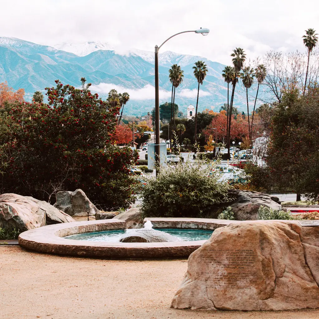 A fountain and landscaping in downtown Ojai with mountains beyond.