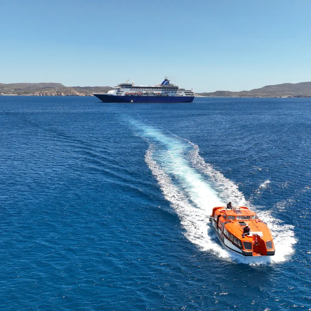 A cruise tender crossing open water with its ship in the distance