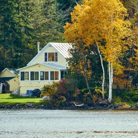 A lakeside cottage and autumn trees beside Rangeley Lake in Oquossoc, Maine.