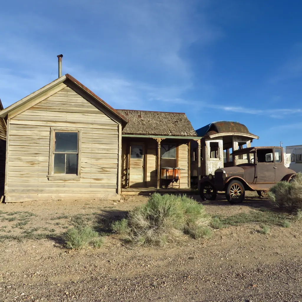 An old wooden house and vehicles in Goldfield, Nevada.
