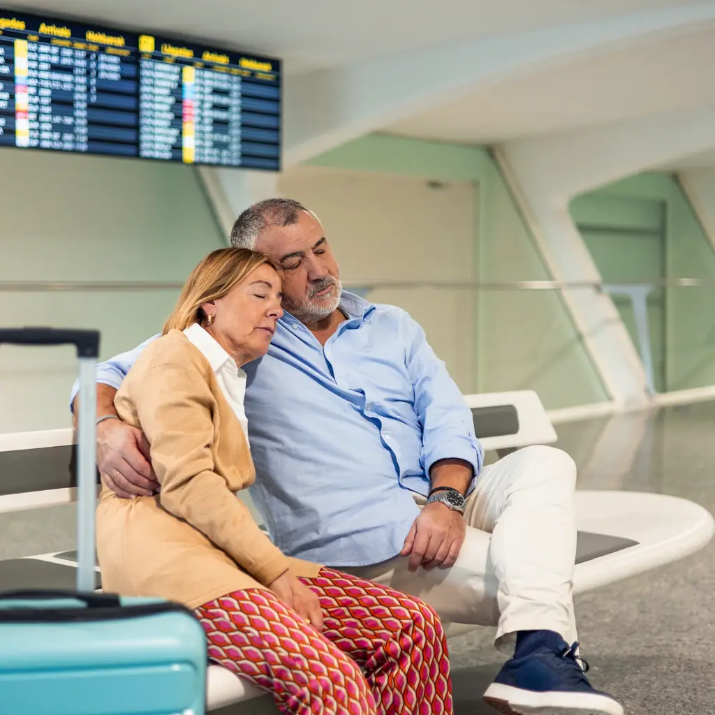 An older couple resting on seats at an airport