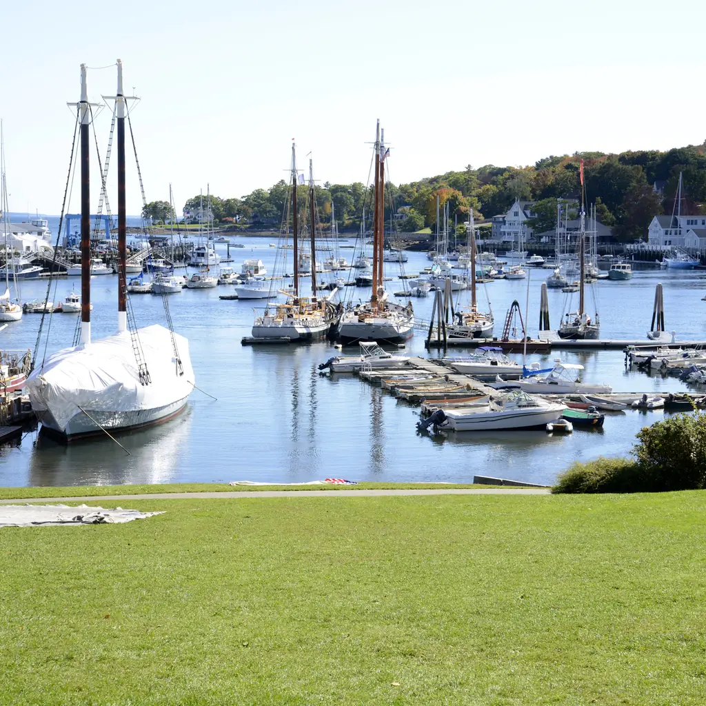 Sailboats and a green waterfront lawn beside Camden Harbor in Maine.