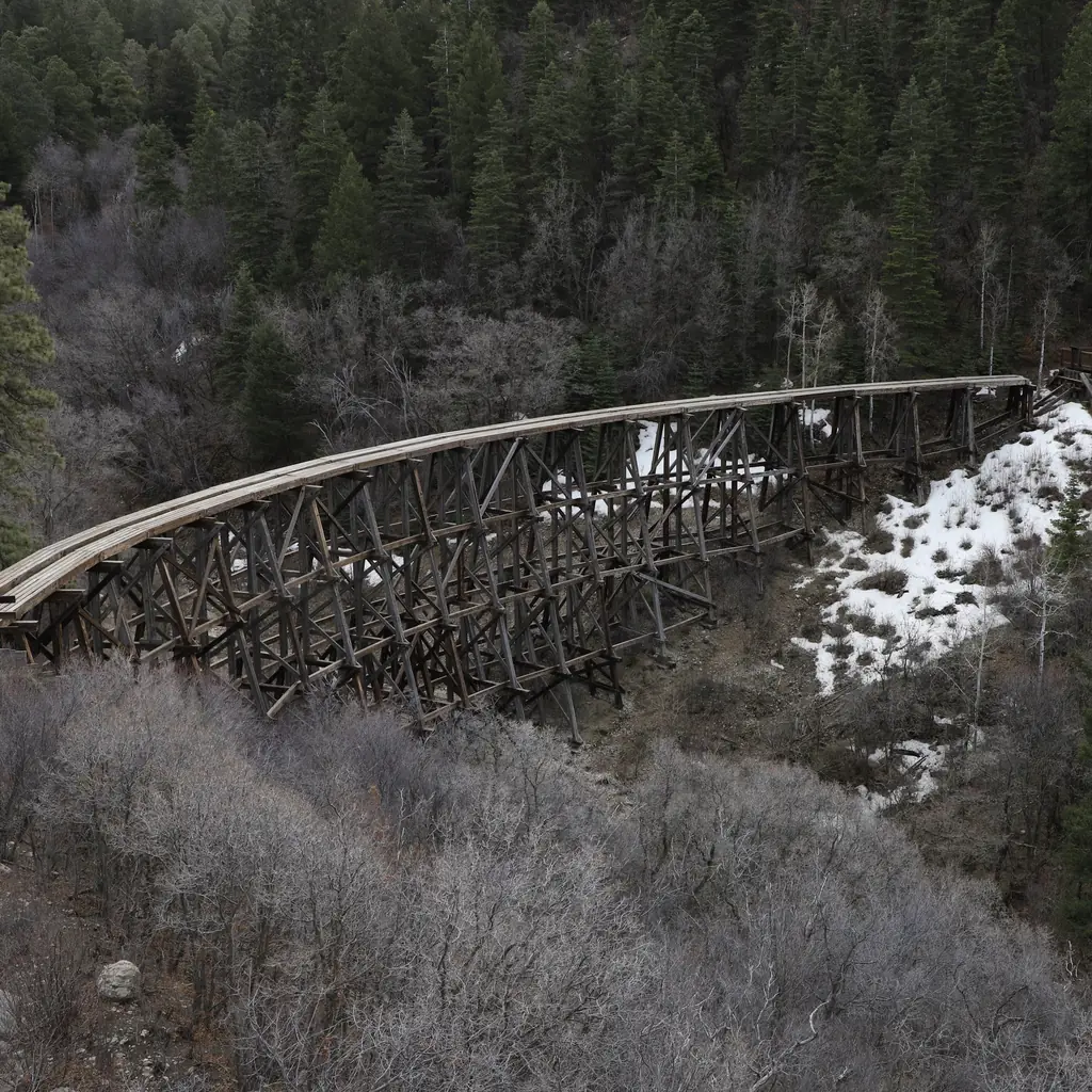 A preserved wooden railroad trestle near Cloudcroft, New Mexico, with patches of snow beside it.