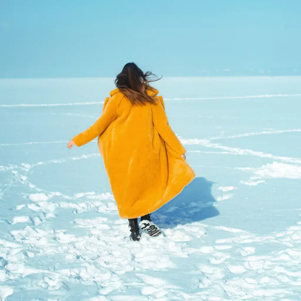 The hem of a long wool coat dragging through salted slush on a sidewalk