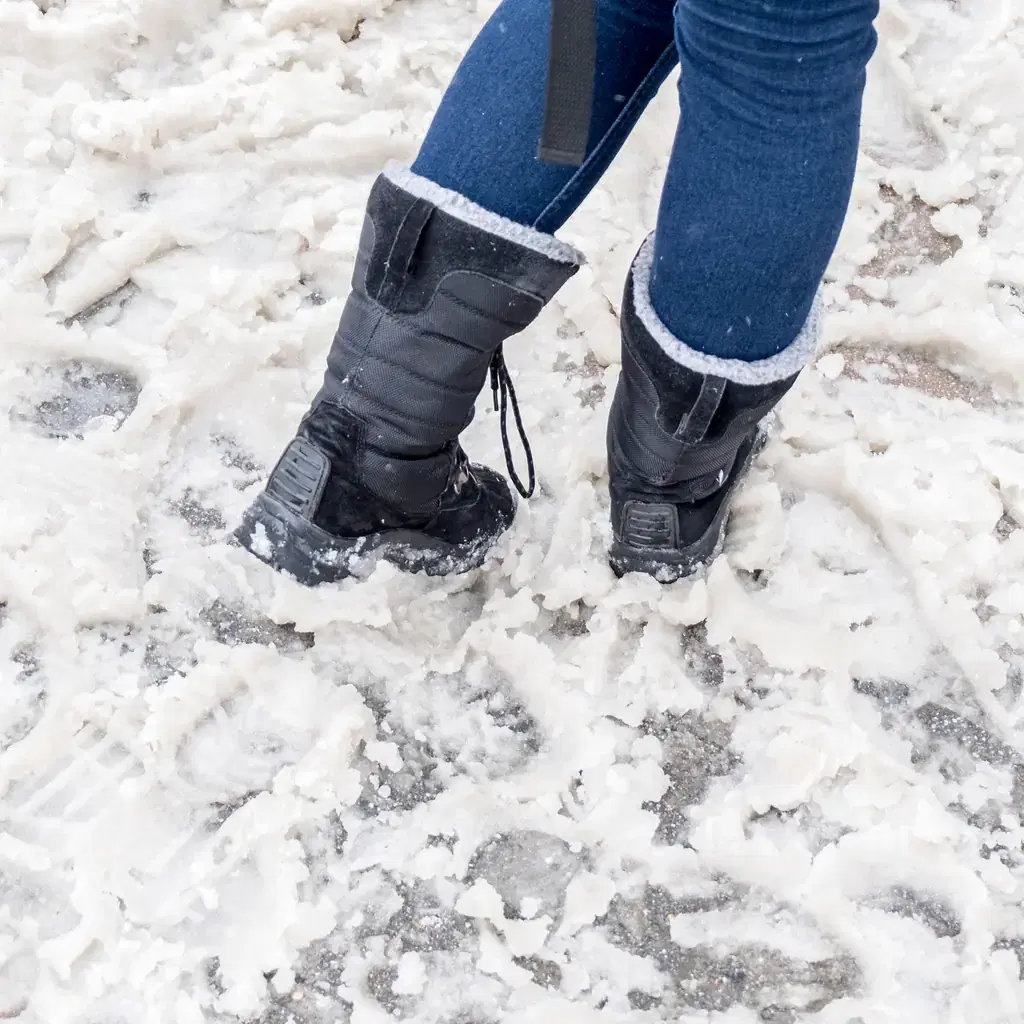 Chunky insulated snow boots on a salted city sidewalk