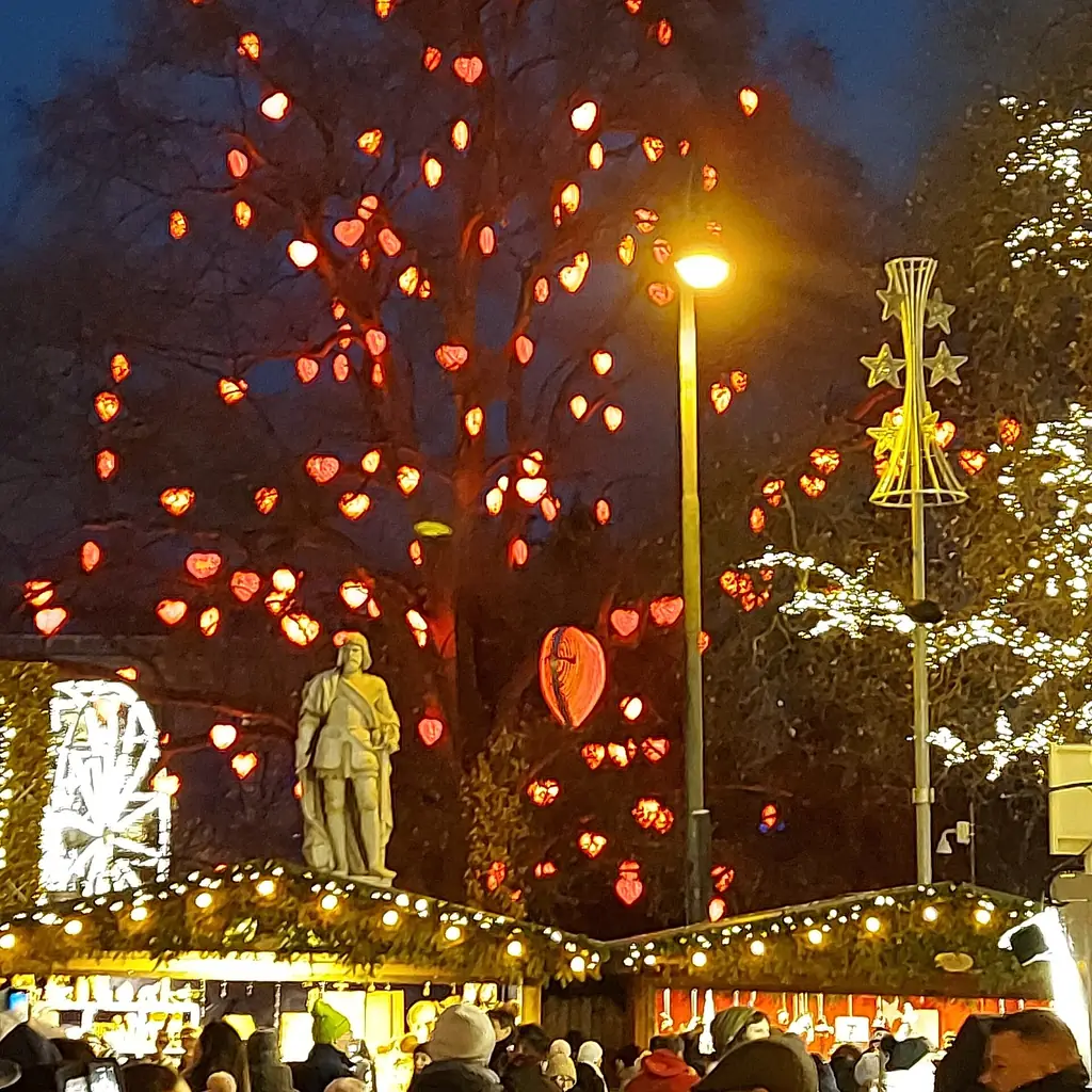The Vienna Christkindlmarkt on Rathausplatz at night with lit stalls and the Rathaus behind