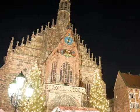 The Frauenkirche lit up at night above the Nuremberg Christmas market and its glowing Christmas trees