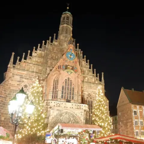 The Frauenkirche lit up at night above the Nuremberg Christmas market and its glowing Christmas trees