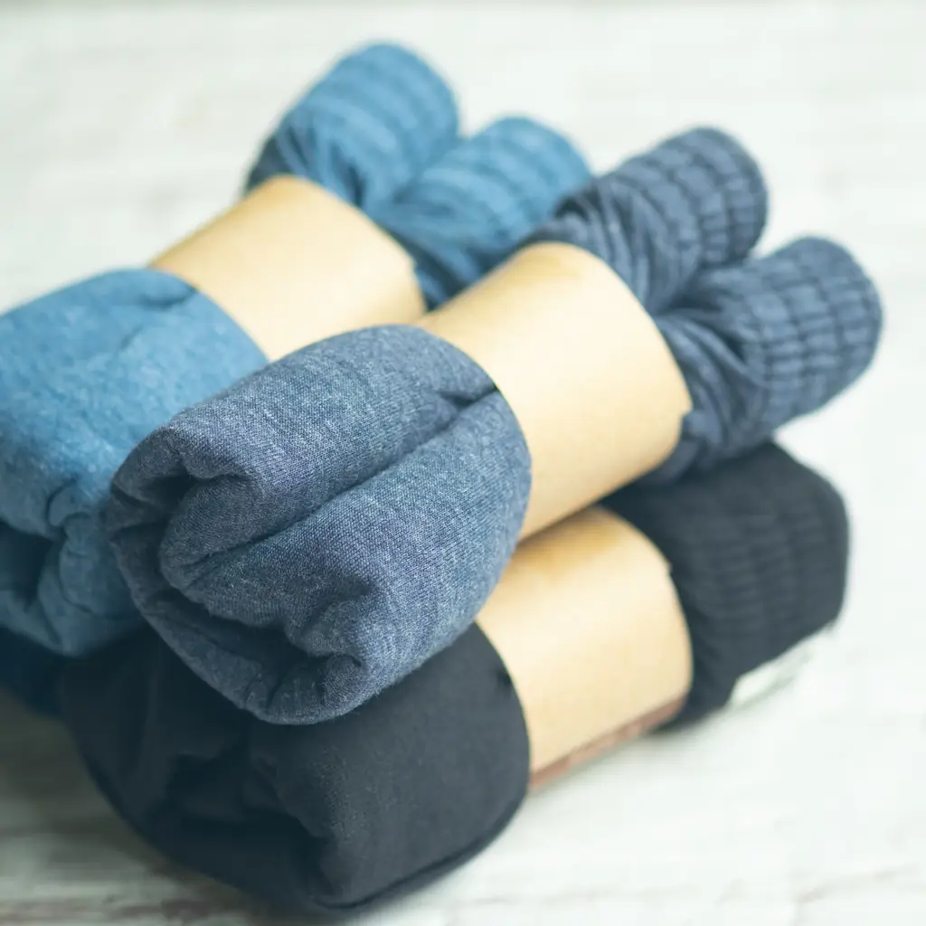 Wool socks in two thicknesses laid out, with a rolled spare pair tucked into a day bag's side pocket