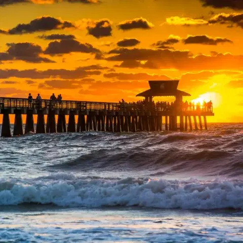 The wooden Naples Pier stretching into the Gulf of Mexico under a clear sky