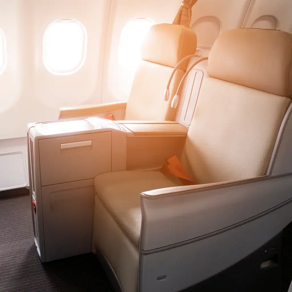 A cream leather business class seat inside a high-walled private suite beside the cabin windows