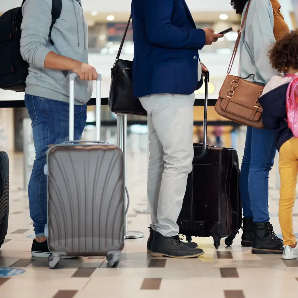 A crowded airport terminal with long lines of travelers and roller suitcases