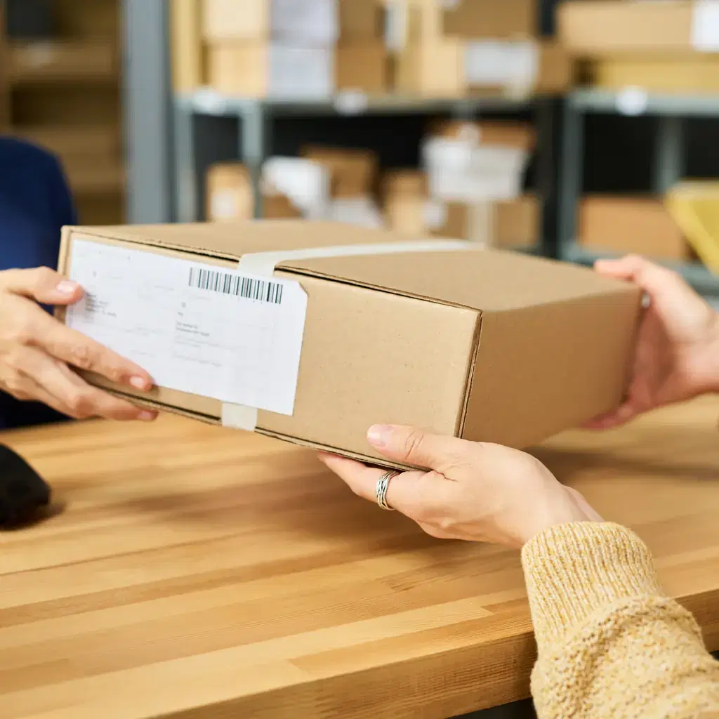 A taped parcel being handed across a shipping counter